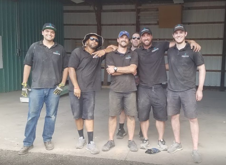 Six Armada movers — CSU students and alumni — arm in arm at the company warehouse in Fort Collins